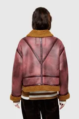 Chaqueta corta azul con efecto desgastado y cuello de piel sintética. Cuenta con cierre frontal con cremallera, dos bolsillos laterales con cremallera y puños y bajo con ribete de piel sintética.