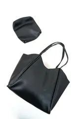 Bolso tote negro de cuero sintético con diseño estructurado y asas dobles de hombro. Incluye un práctico neceser o estuche pequeño a juego con cierre.