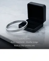 Esclava rígida de acero inoxidable con diseño grabado de guarda griega en toda su superficie.