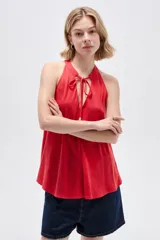 Musculosa de viscosa color rojo, con cuello halter, corte ajustado al cuerpo y detalle de cordones con cuentas en el escote.
