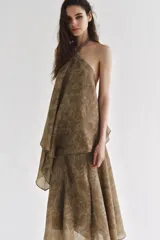 Top de cuello halter con tiras cruzadas para atar al cuello, hombros descubiertos y bajo asimétrico con caída drapeada y textura rústica con estampado sutil.