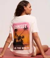 Remera alargada de algodón color crema con estampa de palmeras y atardecer en la playa.