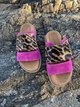 Sandalias bajas con base color suela, tira ancha de cuero fucsia y tira superior de animal print.