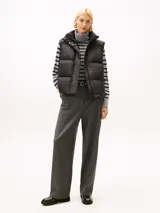 Chaleco acolchado de corte regular, confeccionado en poliéster reciclado. Presenta cuello alto con cierre de botones a presión, cierre frontal de cremallera oculto y diseño sin mangas. Incluye detalles distintivos y logo de la marca.