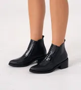 Bota corta de cuero vacuno color negro, con diseño combinado de cuero liso y cuero con textura de reptil en el empeine. Presenta punta fina, taco cuadrado de 6 cm y doble cierre lateral.
