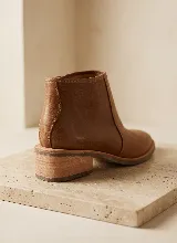 Bota corta de cuero vacuno en color bordó, con diseño combinado de cuero liso y textura de reptil. Cuenta con taco cuadrado de 5 cm, suela de caucho antideslizante y cierre lateral.