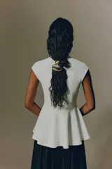 Top en punto roma de color blanco, entallado al cuerpo, con manga japonesa, cuello alto y un delicado peplum con vuelo en la parte inferior.