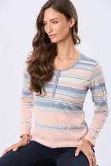 Remera de manga larga con estampado de rayas horizontales en tonos rosados, beige y verde. Presenta un escote redondo con una pequeña abertura frontal con botones y aberturas laterales en el ruedo.