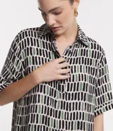Vestido corto en viscosa con estampado de pinceladas en tonos negro, verde y blanco. Tiene cuello solapa, mangas cortas, abotonado delantero y volado en el bajo.