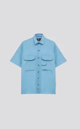 Camisa de manga corta, color celeste, con cuello camisero y calce relajado (relax fit). Presenta cuatro bolsillos cargo frontales con tapa y cierre frontal de botones.