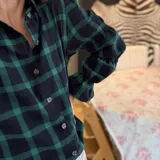 Camisa de manga larga con estampado de cuadros en tonos rojos, blancos y azules. Presenta un diseño con mangas abullonadas divididas por secciones elásticas y cierre frontal con botones.