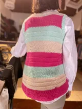Chaleco tejido a mano de hilo de algodón, con diseño de franjas horizontales en colores fucsia, celeste, negro y detalles en amarillo flúor, escote en V y cierre frontal con botones.