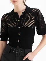 Cardigan negro tejido de textura liviana con puntos calados, escote con cuello polo, mangas cortas abullonadas y cierre frontal con botones dorados.