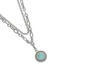 Collar de acero plateado con doble cadena de eslabones y dije redondo con piedra sintética color turquesa. El dije tiene un borde trenzado.