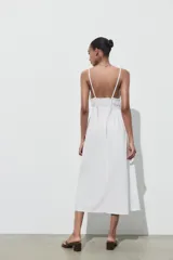 Vestido midi blanco de popelín con escote pico pronunciado, tirantes finos ajustables con cordones y detalle de frunces en la cintura.