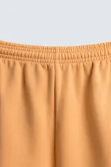 Bermuda de corte relajado confeccionada en tejido de algodón con interior de rizo. Presenta cintura elástica con cordón ajustable, bolsillos laterales, un bolsillo trasero de plastrón y bajo con acabado irregular con efecto lavado.