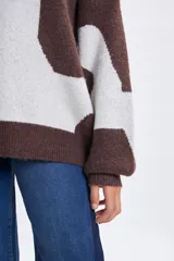 Buzo de punto con diseño jacquard de manchas abstractas en tonos marrón y crema, de corte holgado, cuello redondo y mangas largas con puños ajustados.