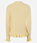 Suéter de tricot color amarillo claro, de manga larga y cuello redondo. Presenta detalles de volados acanalados en el ruedo y en los puños.