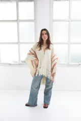 Ruana artesanal color crudo con rayas horizontales color ladrillo y flecos.