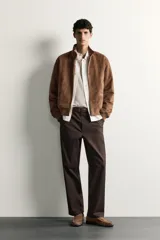 Pantalón chino de corte regular, color marrón oscuro, con cierre frontal de cremallera y botón, bolsillos laterales y bolsillos traseros de vivo.