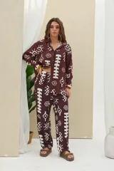 Pantalón de color marrón oscuro con estampado geométrico y tribal en color blanco, de corte recto y tiro medio con cordón ajustable en la cintura.