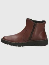 Bota tipo Chelsea de cuero color marrón, con paneles elásticos laterales en color negro y suela de goma dentada.