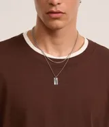 Collar doble dorado con cadena fina y dije rectangular.