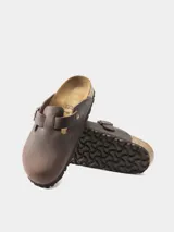 Zuecos Birkenstock Boston de cuero engrasado color marrón oscuro, con plantilla anatómica de corcho y látex, y hebilla metálica ajustable.