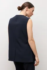 Chaleco largo sastrero de color negro, con escote en V profundo, cierre frontal con un botón metálico y bolsillos laterales con solapa.