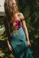 Vestido largo de tejido de algodón con lúrex dorado, de corte recto con tajo lateral. Presenta escote recto con detalle de flores tipo roseta en color rosado en el frente y breteles finos.