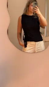 Musculosa negra de lino con breteles finos, corte ajustado y lazos laterales para atar.