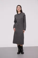 Vestido midi gris de tejido de punto, con cuello redondo y mangas largas. Presenta ribete negro en cuello, puños y hombros.