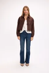 Chaqueta de efecto gamuza en color marrón, con diseño de inspiración western que presenta flecos en la parte frontal y en la espalda. Cuenta con cuello clásico, cierre frontal con botones metálicos a presión y mangas largas.