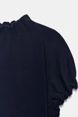 Top de punto color azul marino, con cuello redondo y mangas cortas abullonadas con acabados elásticos fruncidos.