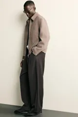 Pantalón de corte balloon fit confeccionado en tejido con viscosa. Presenta cintura ajustable con cinturón integrado, pliegues frontales, bolsillos laterales y bolsillos traseros de doble vivo. Cierre frontal con cremallera y botón.