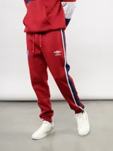 Pantalon de jogging azul de felpa, con franjas laterales en blanco y azul marino. Presenta el escudo del Club Nacional de Football en el muslo derecho y el logo de Umbro en el izquierdo.