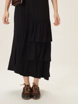 Vestido midi de morley color negro, con escote en V, mangas cortas y diseño con volados asimétricos en el lateral inferior.