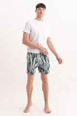 Short de baño con estampado de hojas tropicales en tonos verdes y detalles en naranja. Cuenta con cintura elástica con cordón ajustable.