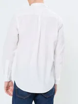 Camisa blanca de popelina de algodón flexible, con cuello abotonado, cierre frontal con botones y puños abotonados. Tiene logo de Tommy Hilfiger bordado en el pecho.