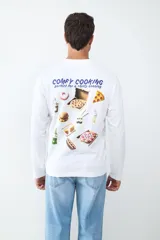 Camiseta de manga larga color blanco, con cuello redondo y estampado pequeño en el pecho con la frase 'Comfy Cooking'.