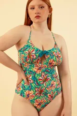 Malla entera de lycra estampada con flores de colores sobre fondo turquesa. Tiene breteles finos que se cruzan en la espalda y detalle de moño en el escote.
