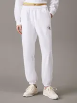 Pantalón de jogging blanco de felpa de mezcla de algodón, con cintura elástica con cordón ajustable, bolsillos laterales, bajos de canalé y monograma CK en la pierna. Corte tapered y largo estándar.