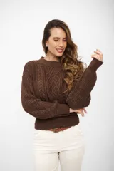 Sweater de punto con cuello redondo, diseño de trenzas frontales y acabado con hilo metálico brillante. Presenta puños y cintura ajustados en tejido acanalado.