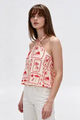 Top de viscosa con escote halter, tirantes finos, diseño holgado y estampado de motivos veraniegos en tonos rojos sobre base beige.