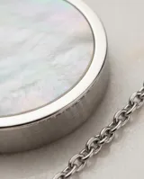 Collar de cadena fina de acero con dije colgante compuesto por dos círculos entrelazados, uno de acero liso y otro con incrustación de nácar en el centro.