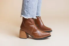 Botas cortas de cuero color marrón con detalle de cuero texturizado en el empeine y cierre lateral.