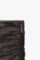 Falda pantalón de tiro medio color marrón oscuro, con detalle de volantes y cierre lateral con cremallera oculta.