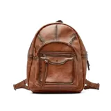 Mochila cartera Korium Vera de cuero sintético en color marrón, con diseño estructurado, bolsillo frontal con cierre y tachas decorativas en la parte superior.