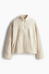 Buzo de corte oversized confeccionado en tejido de sherpa suave. Presenta cuello elevado con medio cierre frontal, hombros caídos y bolsillos insertados en el frente. Incluye canesú en la parte delantera y trasera.