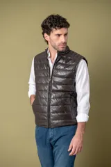 Chaleco acolchado de cuero color marrón, con diseño matelasseado horizontal, cierre frontal y cuello alto.